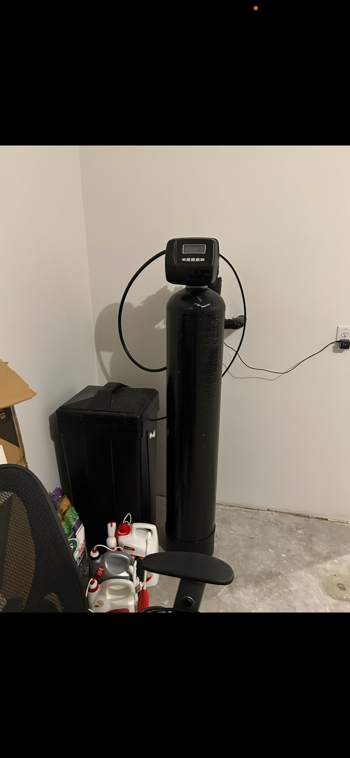 Whole-home water softener installed indoors in garage